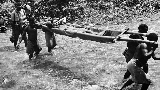 Wounded soldier carried across river by Papuan stretcher bearers